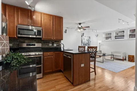 a kitchen with stainless steel appliances granite countertop a refrigerator a stove top oven a sink dishwasher and wooden cabinets with wooden floor