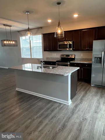 a kitchen with stainless steel appliances granite countertop a sink a stove a refrigerator and a microwave