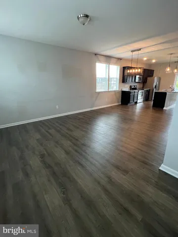 an empty room with hard wood floors and windows