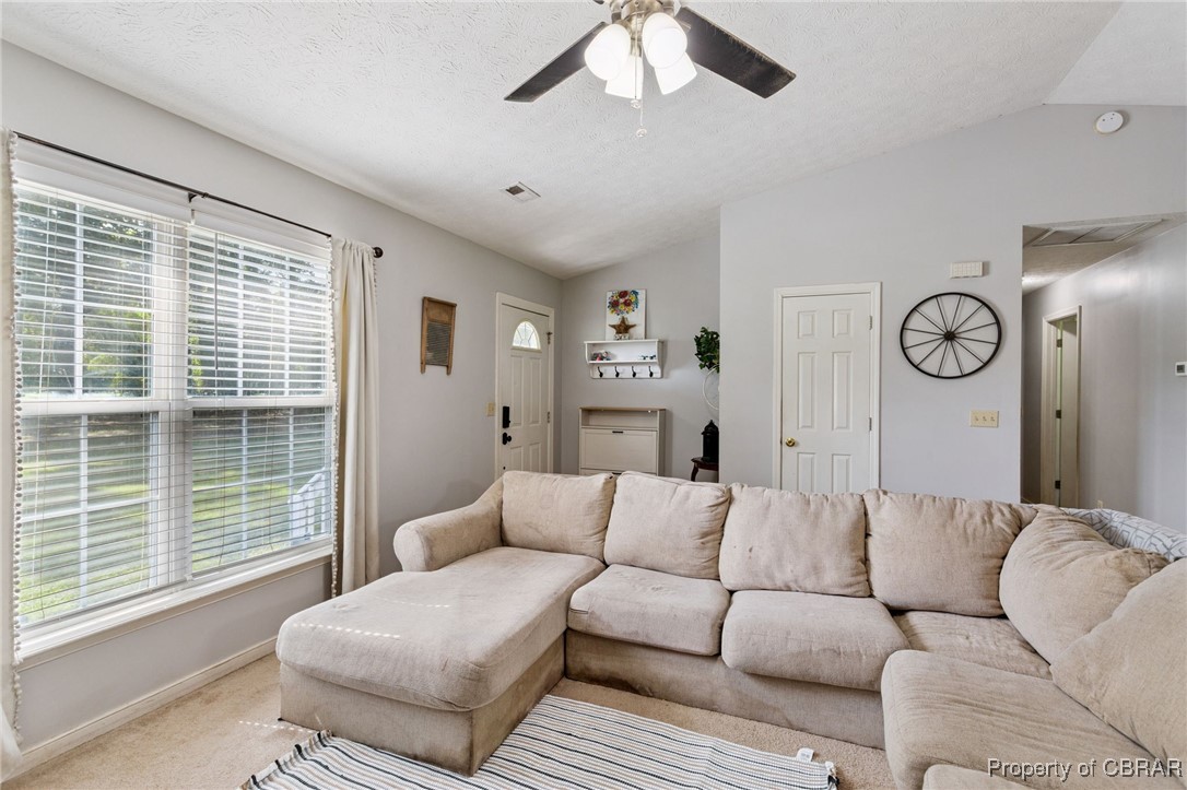 7989 Pinetta Road Gloucester, VA 23061 - Photo 5 of 26 Living area featuring vaulted ceiling, light colored carpet, plenty of natural light, ceiling fan, and a textured ceiling
