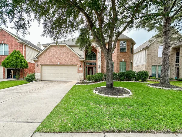 a front view of a house with a yard and large tree