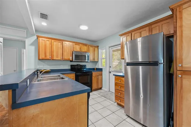 a kitchen with stainless steel appliances granite countertop a refrigerator a stove top oven and a sink