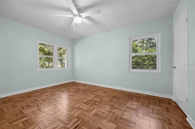 a view of an empty room with window and ceiling fan