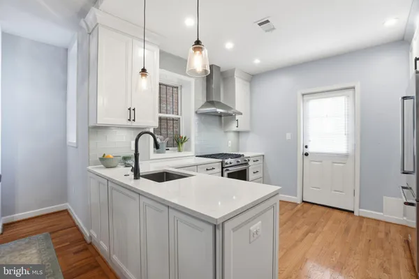 a kitchen with stainless steel appliances granite countertop a sink a stove a refrigerator and island with wooden floor