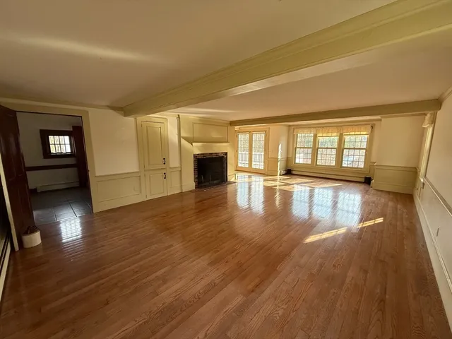 a view of an empty room with window and wooden floor
