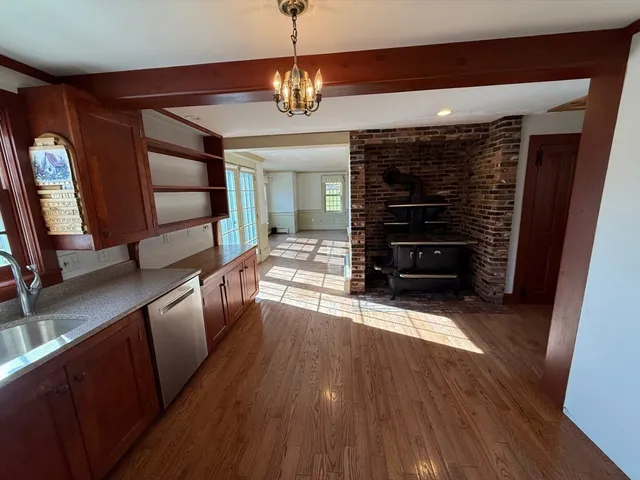 a view of a hallway to a livingroom with wooden floor and furniture