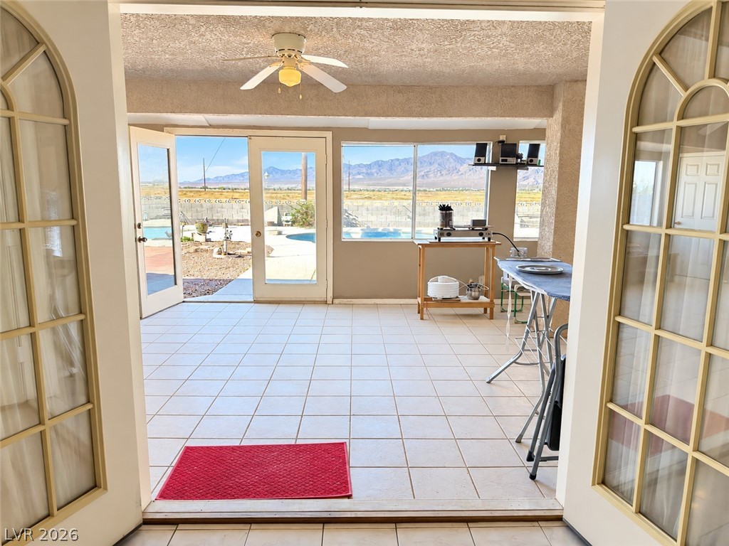 5470 Grain Mill Road Pahrump, NV 89061 - Photo 50 of 80 Double doors off the living room which lead to an enclosed patio and pool view. Tiled sunroom framing picturesque mountain views through glass doors. There are two doors inside the enclosed patio. One leads to the primary suite; the second leads to the secondary primary suite.