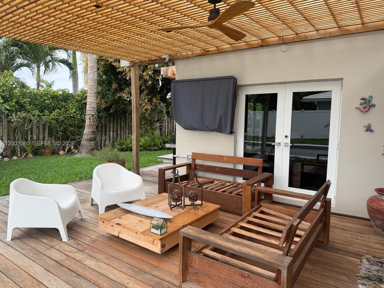 1251 Southwest 11th Terrace Boca Raton, FL 33486 - Photo 37 of 47 a view of a patio with a dining table and chairs with wooden floor and fence