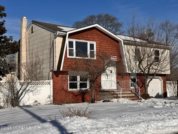 a front view of a house with large trees