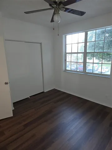 an empty room with wooden floor fan and windows
