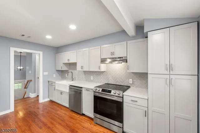 a kitchen with stainless steel appliances white cabinets and wooden floors