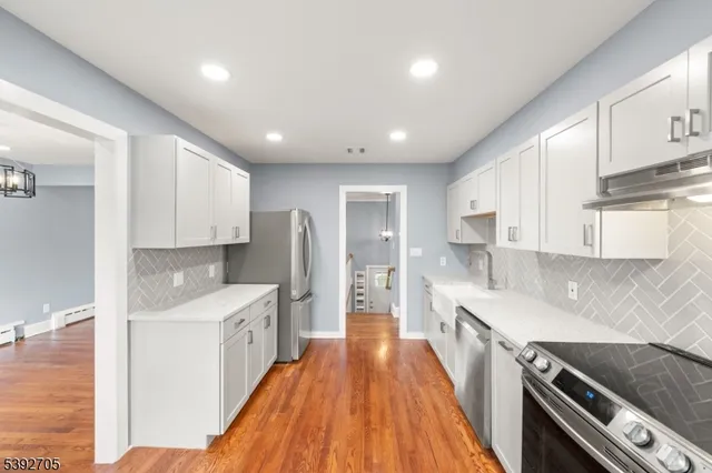 a large kitchen with stainless steel appliances granite countertop a lot of counter space and wooden floor