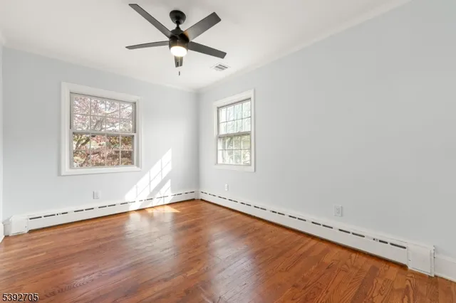 a view of an empty room with window and wooden floor