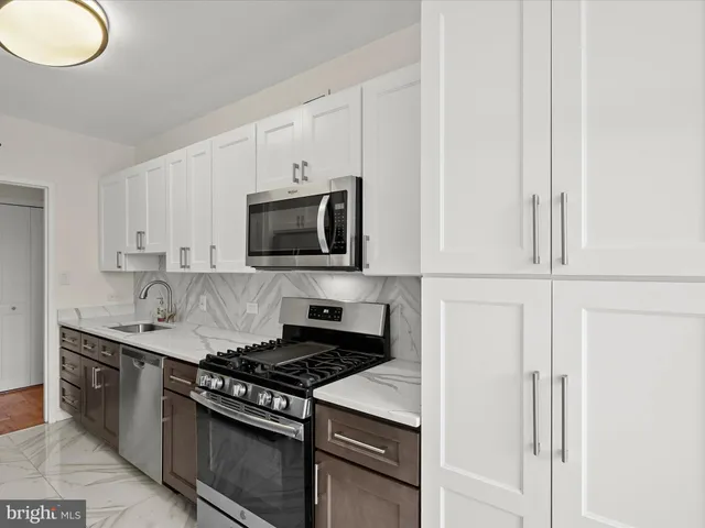 a kitchen with granite countertop a sink a stove and cabinets
