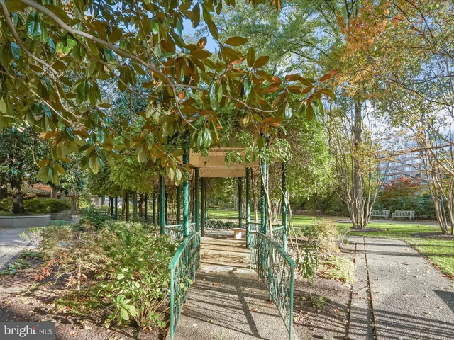 a view of a brick house with large trees and plants