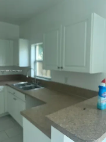 a view of a sink a counter space and cabinets in a room