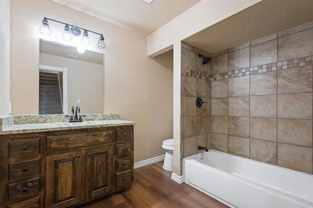 a bathroom with a granite countertop sink a toilet and bathtub