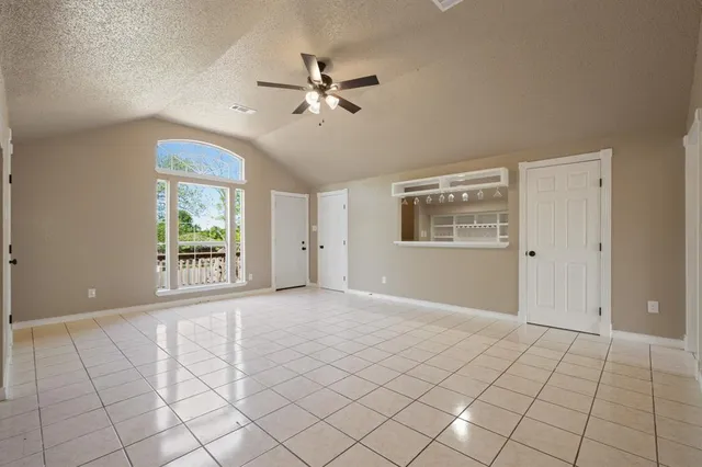 a view of an empty room with window and chandelier fan