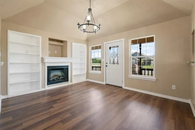 a view of an empty room with wooden floor fireplace and a window