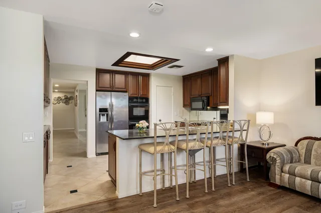 a kitchen with stainless steel appliances granite countertop wooden cabinets a sink a stove a refrigerator and a microwave