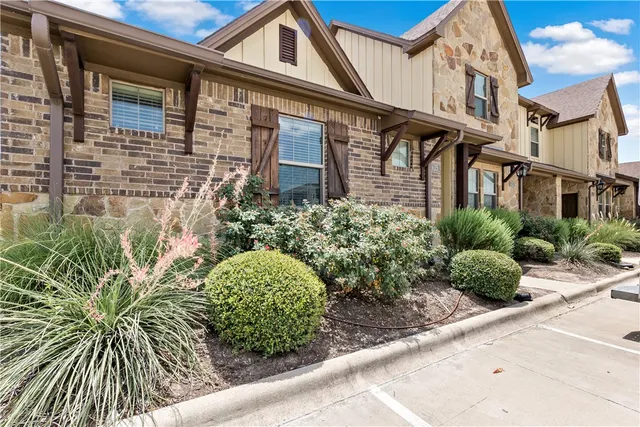 a front view of a multi story residential apartment building with yard and retail shops