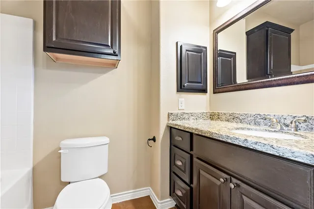 a bathroom with a granite countertop toilet sink and mirror