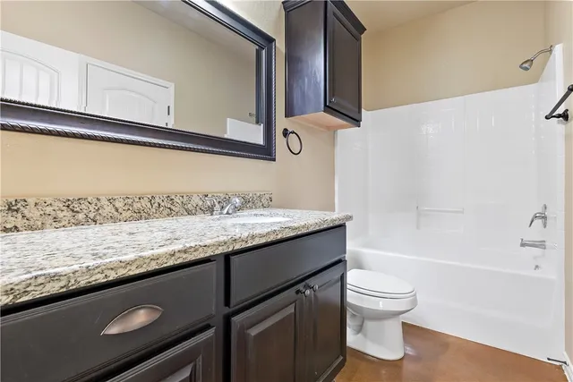 a bathroom with a granite countertop sink a toilet and bathtub