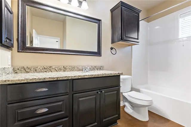 a bathroom with a granite countertop toilet sink and mirror