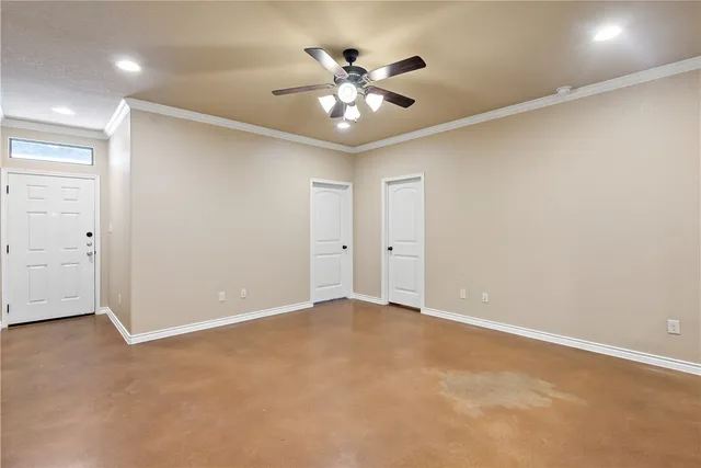 an empty room with chandelier fan and windows