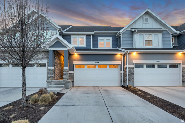 Craftsman house with concrete driveway, stone siding, an attached garage, and board and batten siding