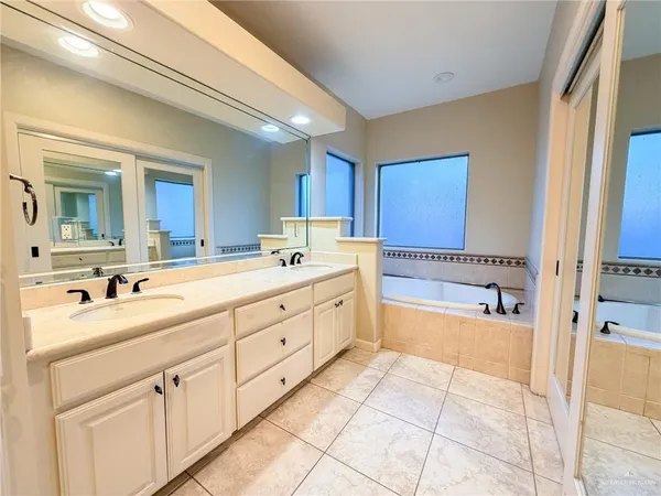 a spacious bathroom with a double vanity sink mirror and bathtub