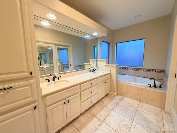 a spacious bathroom with a double vanity sink mirror and bathtub