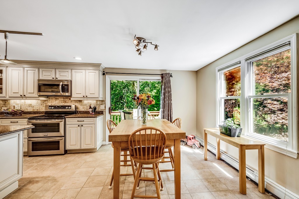 178 Reed Farm Road Boxborough, MA 01719 - Photo 7 of 30 a open kitchen with stainless steel appliances granite countertop a stove top oven a sink dishwasher a dining table and chairs with wooden floor