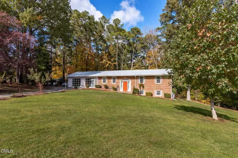 a view of a yard in front of a house with large trees