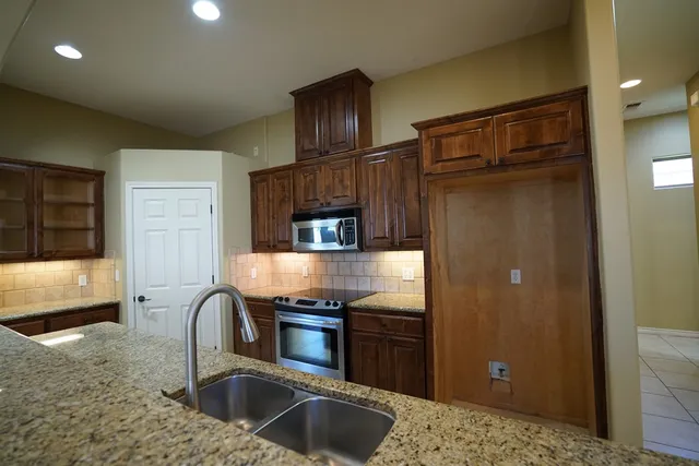 a kitchen with granite countertop stainless steel appliances a refrigerator and a sink