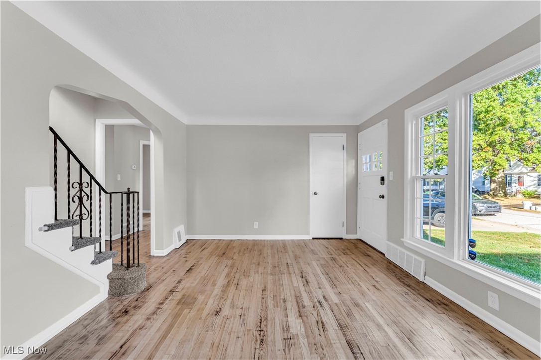 Foyer featuring light wood-style floors, arched walkways, and stairs