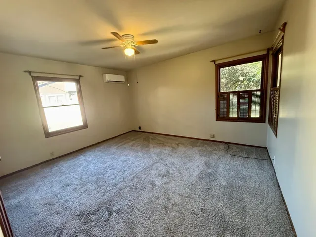 an empty room with windows and chandelier fan