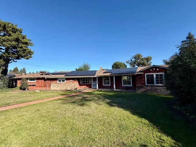 a front view of a house with a garden and lake view