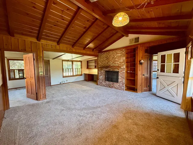 a view of an empty room with a fireplace and a window