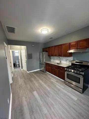 a kitchen with stainless steel appliances granite countertop a stove and a wooden floors