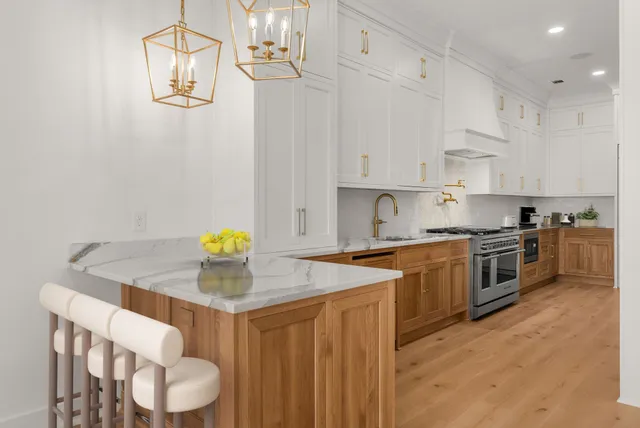 a kitchen with stainless steel appliances granite countertop a sink a stove a chimney a dining table and chairs