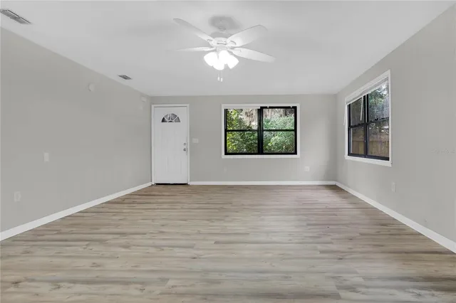 a view of an empty room with window and wooden floor