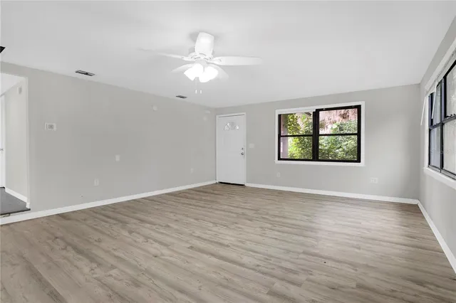 a view of an empty room with a window and wooden floor