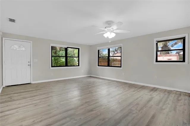 a view of an empty room with a window and wooden floor