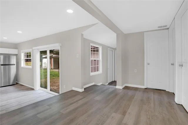 a view of an empty room with wooden floor and a window