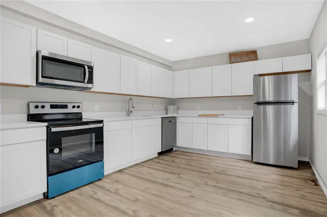 a kitchen with a refrigerator sink and white cabinets