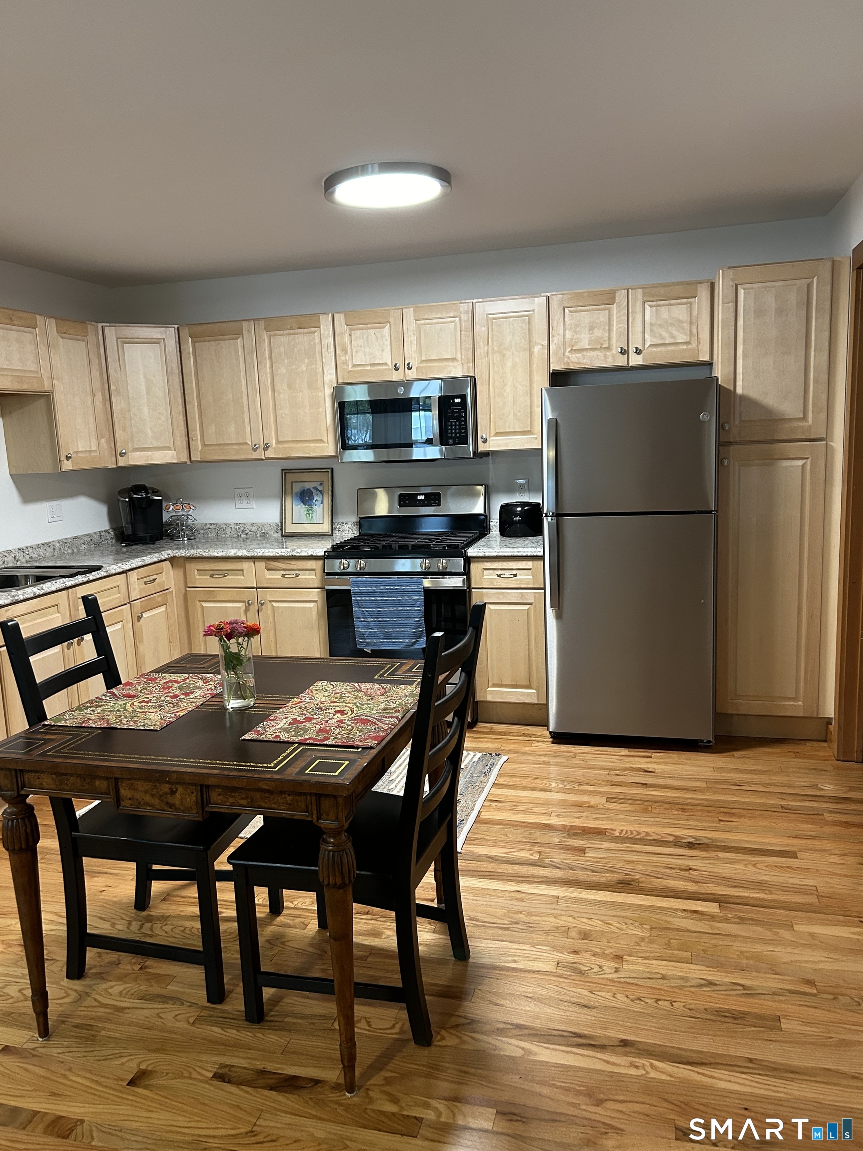 28 Sugar Street, Unit B Newtown, CT 06470 - Photo 7 of 11 a kitchen with a table chairs refrigerator and microwave