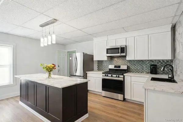 a kitchen with kitchen island granite countertop a sink stainless steel appliances and white cabinets