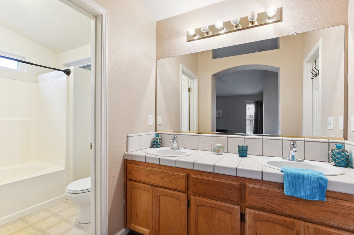 257 Toschi Drive Madera, CA 93637 - Photo 21 of 40 a bathroom with a double vanity sink toilet mirror and bathtub