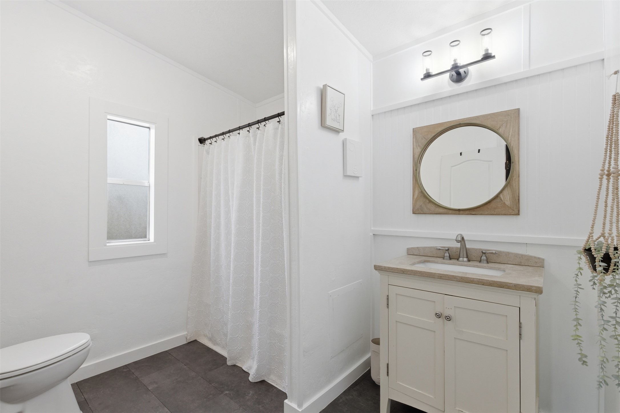 580 Railyard Drive Kyle, TX 78640 - Photo 18 of 20 This bathroom features a single vanity with a stone countertop, an oval mirror with a decorative frame, and a shower with a white curtain